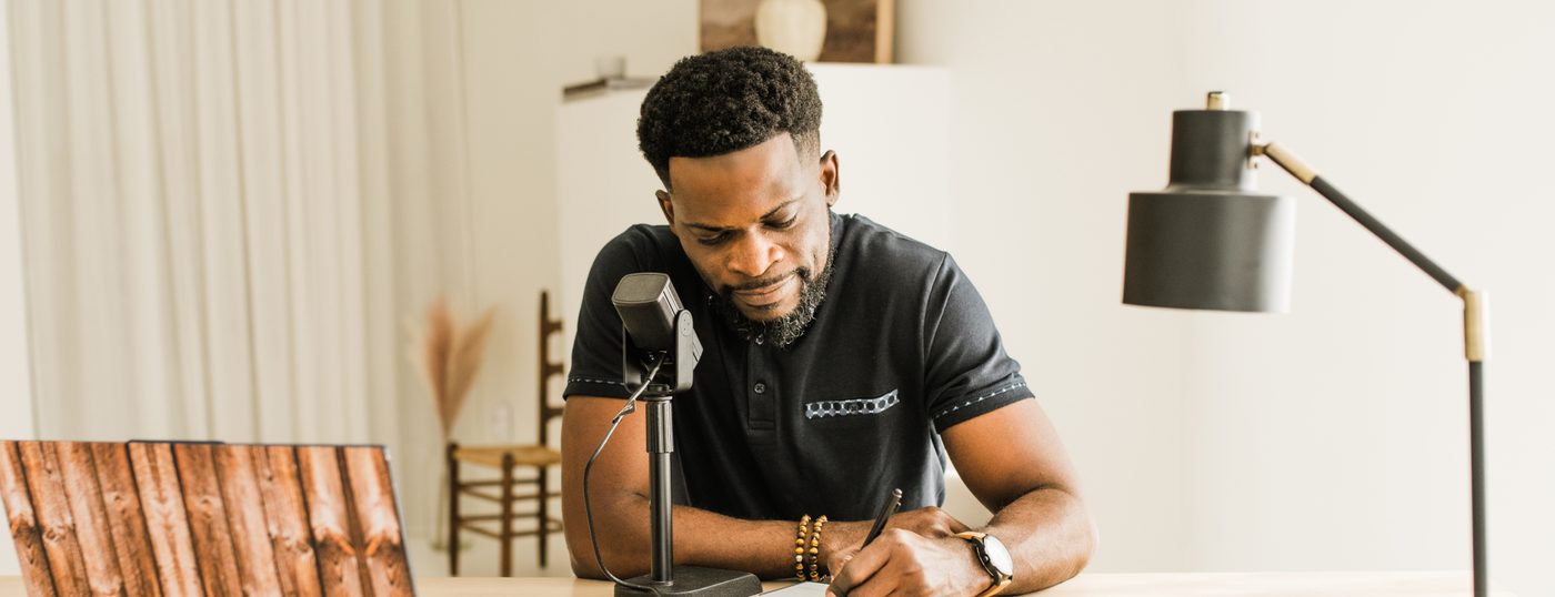 Seun Adeyemi writing at his desk beside a microphone